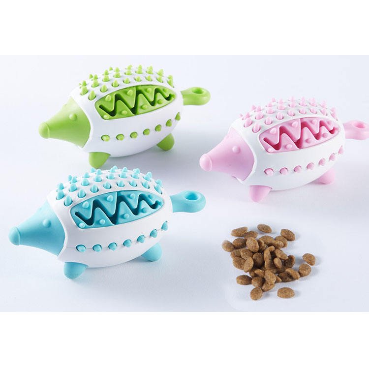 Balles distributrices de croquettes en silicone bleu, vert et rose avec quelques croquettes