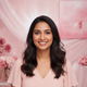 Portrait headshot of a smiling South Asian woman in her late 20s with a warm, trustworthy expression. The background is softl